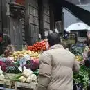 man in brown coat standing in front of fruit stand