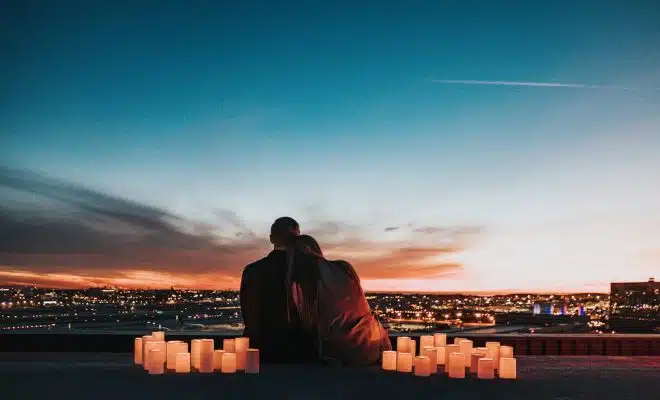 couple sitting on the field facing the city